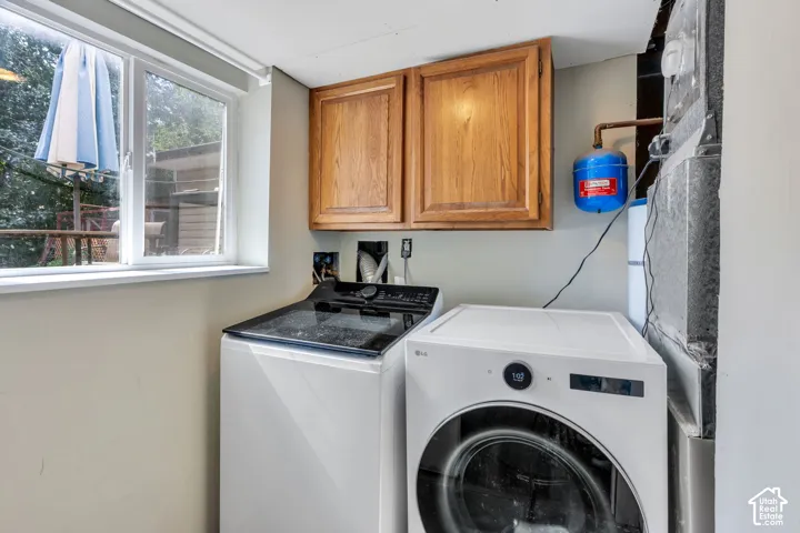 Laundry area with a window, wood-finish cabinetry, and utility connections