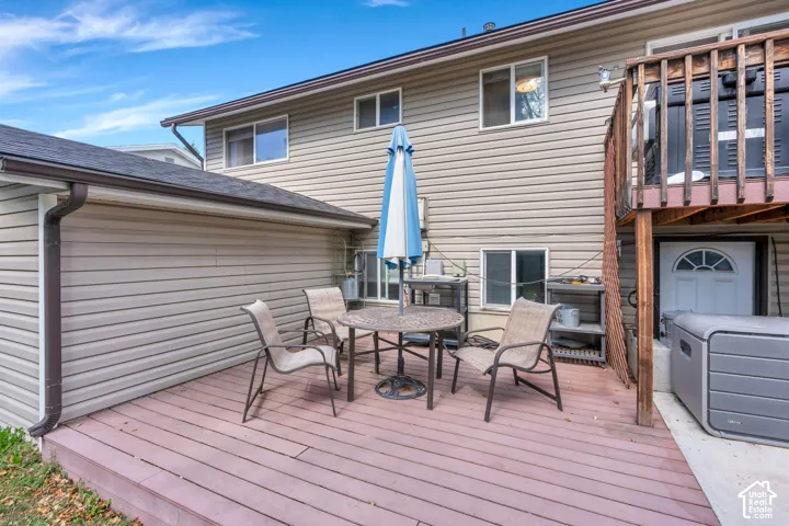 Expansive wood-finish deck with ample space for outdoor furnishing, complemented by a multi-level structure featuring an upper wood-railed deck and a lower-level entry door