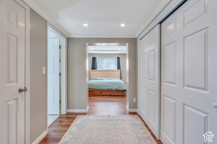 Hallway featuring wood-finish flooring, recessed lighting, white paneled doors, and crown molding
