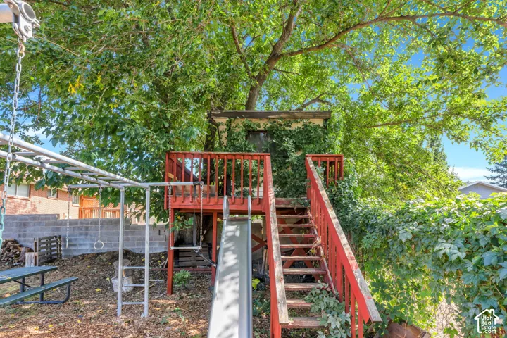 Backyard featuring a red-stained wooden play structure with stairs, an attached slide, and an overhead monkey bar set