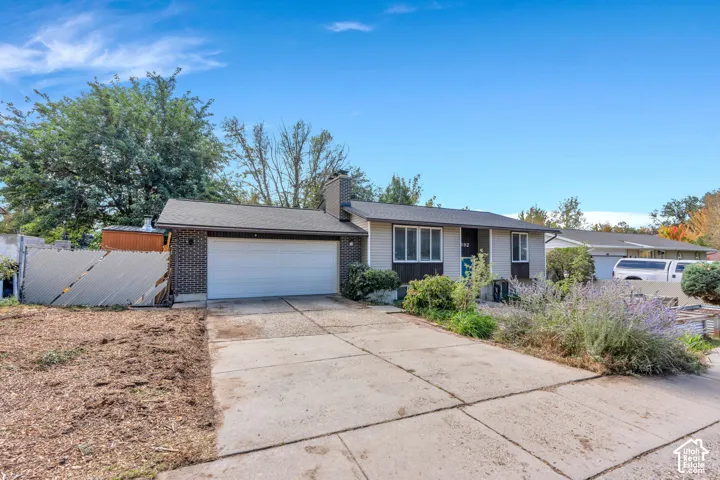 Split-level residence featuring a two-car garage, brick facade detailing, and a concrete driveway