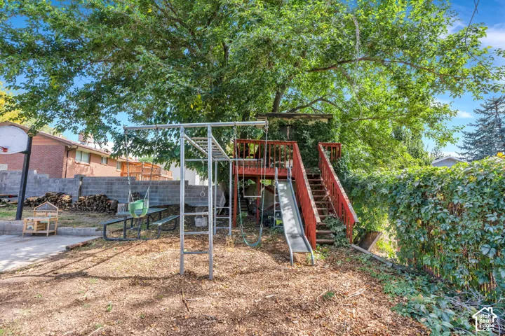 Expansive backyard featuring a mature tree, terraced landscaping, and a retaining wall