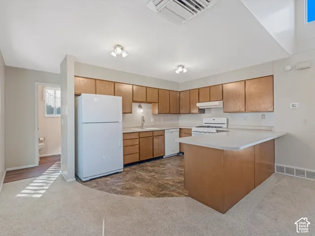 Kitchen featuring wood cabinetry, white appliances, a gas range, and a breakfast bar