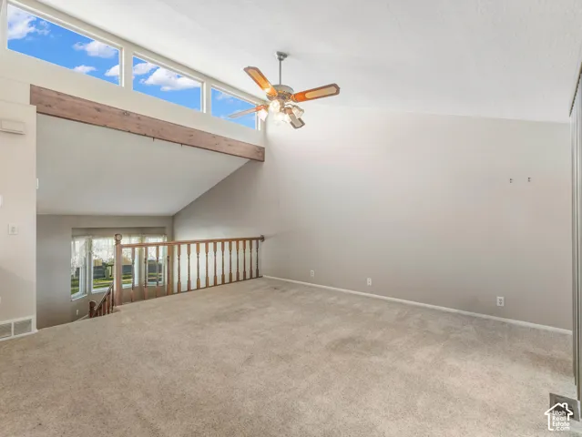 Vaulted ceiling with a wood-finish beam, high clerestory windows, and a ceiling fan