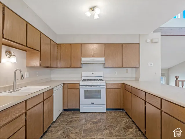 U-shaped kitchen layout featuring wood-finish cabinetry, white countertops, and a white gas range