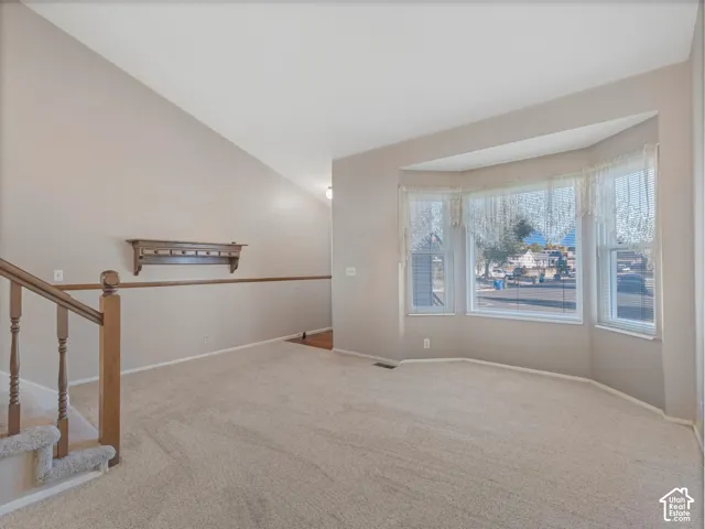 Bay window with white trim, vaulted ceiling, and built-in wood shelf