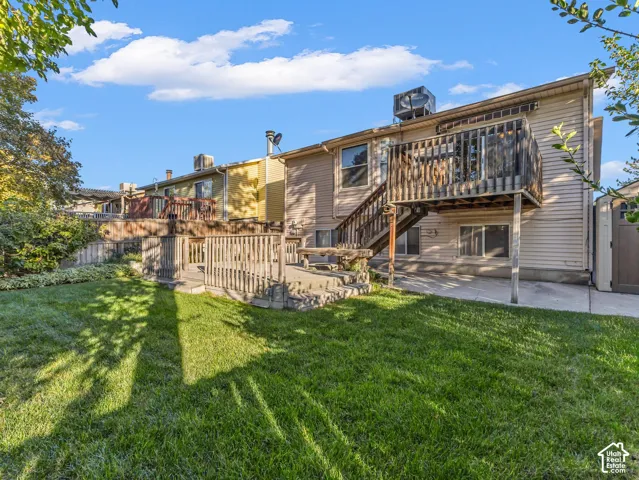Expansive backyard featuring a manicured lawn, multi-level wood deck, and concrete patio