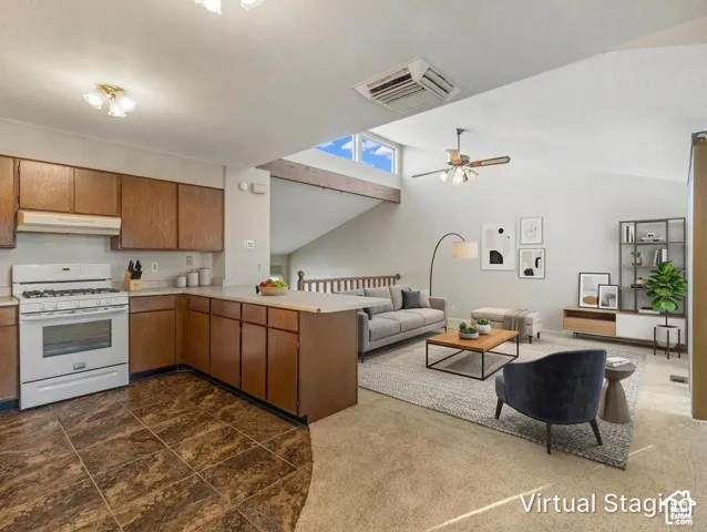 Kitchen featuring wood cabinetry, white range, and tiled flooring, accented by a vaulted ceiling with exposed wooden beam, clerestory window, and ceiling fan