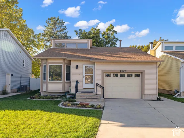 Siding exterior with a bay window, attached single-car garage, concrete driveway, and front lawn