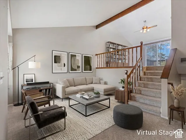 Vaulted ceiling with exposed wood beam, built-in shelving, carpeted staircase with wood railing, and ceiling fan fixture