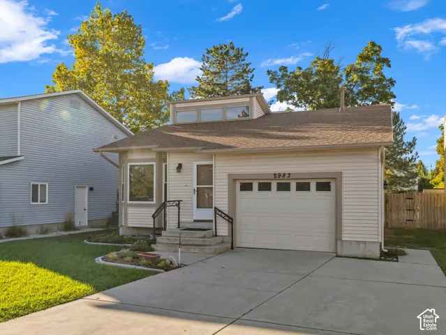 Single-car garage with an overhead door, concrete driveway, front entrance with steps and wrought iron railings, and a dormer with transom windows