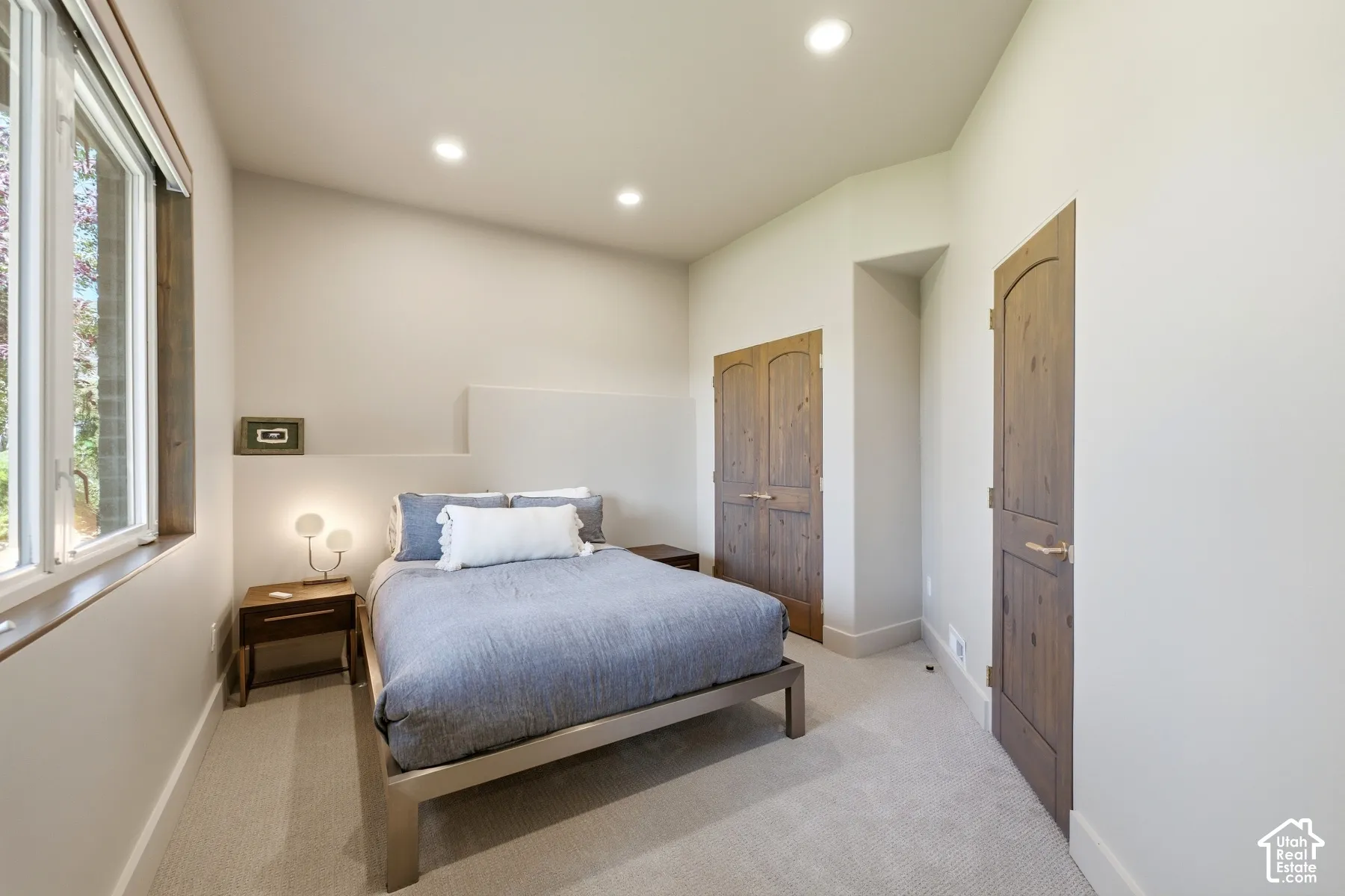 Vaulted ceiling featuring recessed lighting, large window with wood-finish trim, and natural wood-finish doors