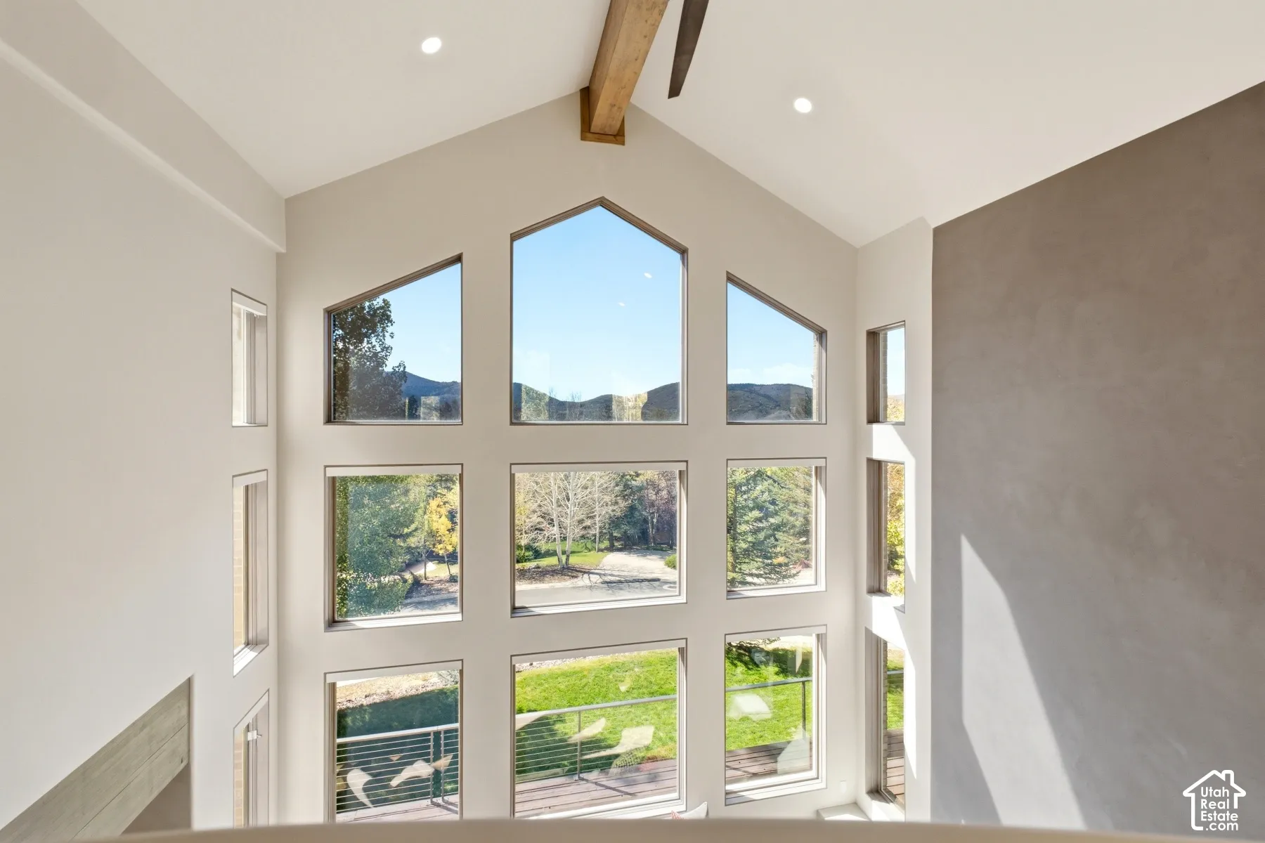 Vaulted ceiling with exposed wood beam, recessed lighting, and a multi-pane window wall