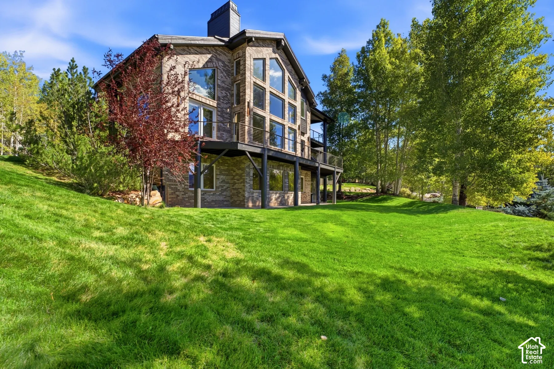Stone exterior with extensive fenestration, multiple balconies, and a chimney