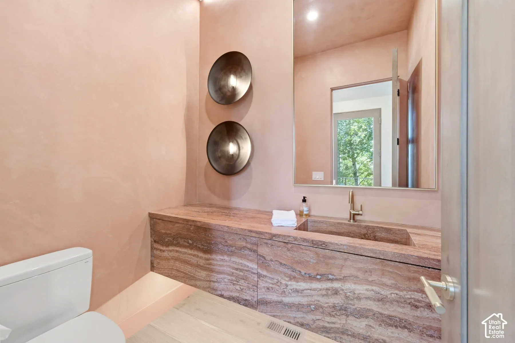 Integrated stone vanity with a rectangular basin, wall-mounted faucet, and illuminated sconces