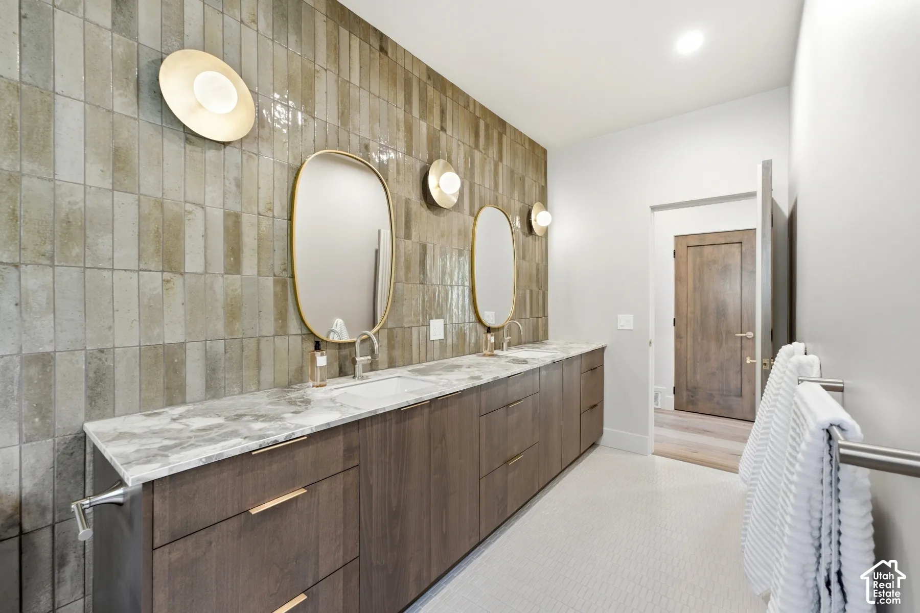 Double vanity with a stone countertop, built-in cabinetry, dual mirrors, and wall-mounted sconces