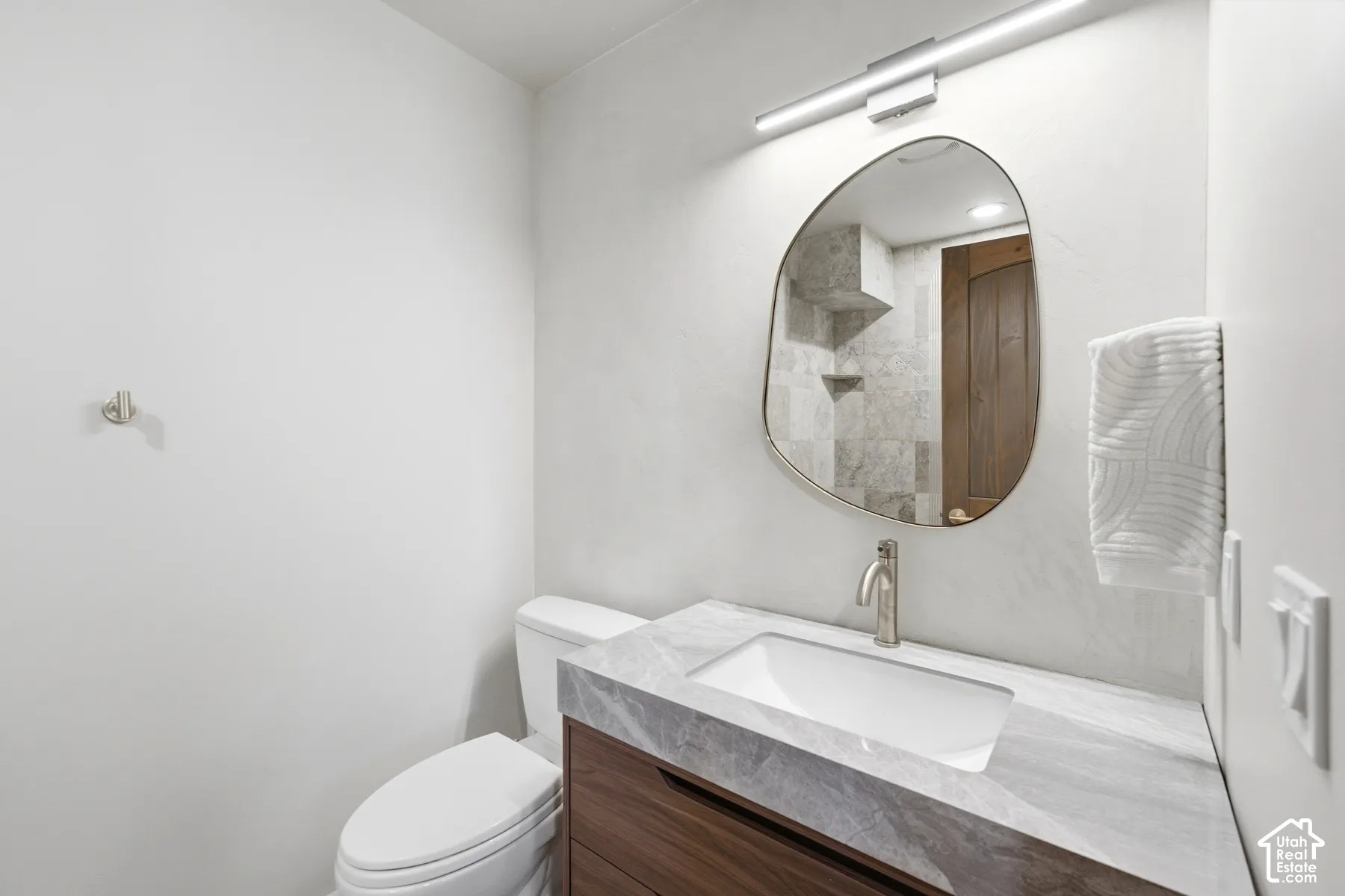Contemporary vanity with a rectangular undermount sink, stone-finish countertop, and wood-finish cabinetry