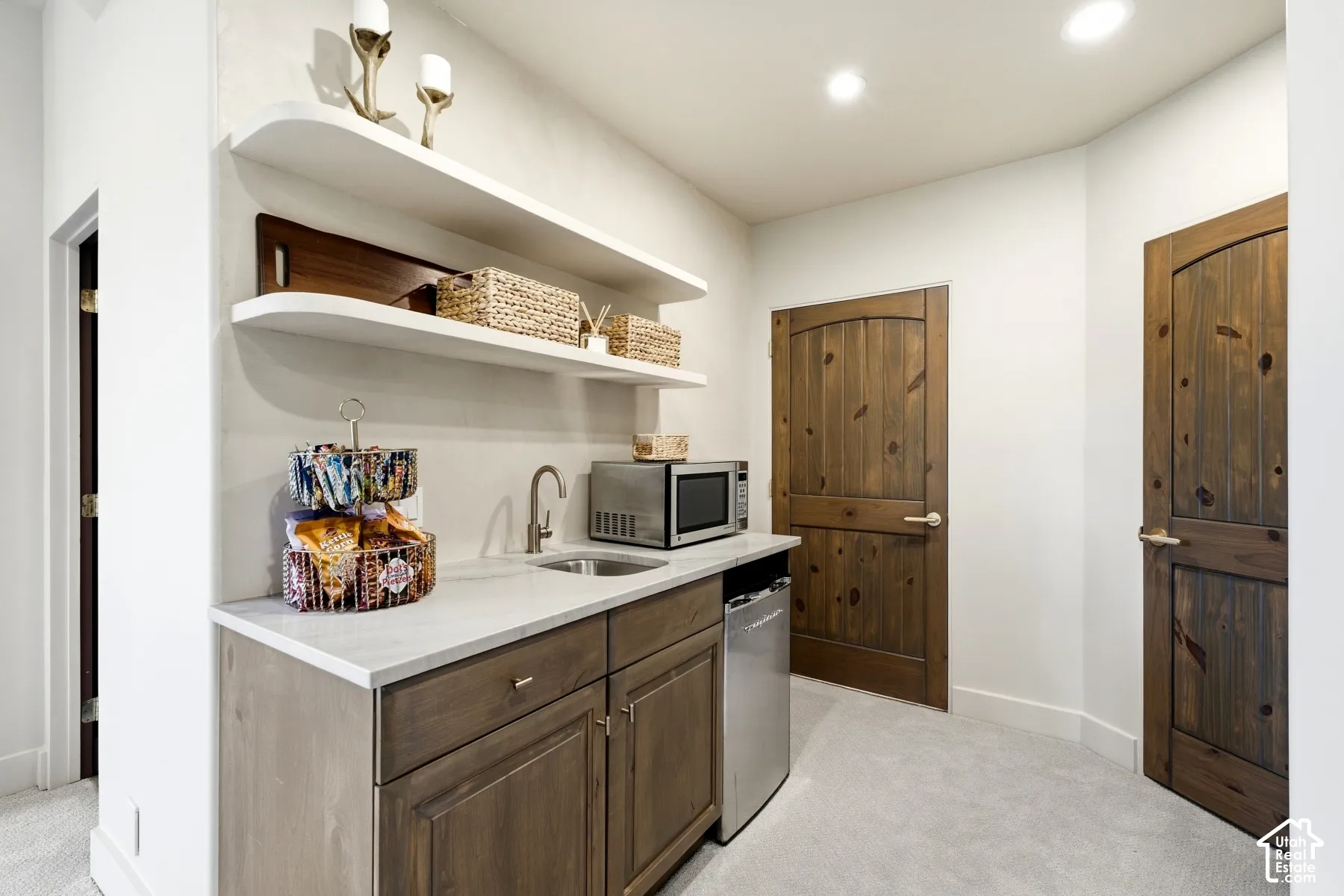 Built-in cabinetry with a light stone countertop, an undermount sink, and a stainless steel mini-refrigerator