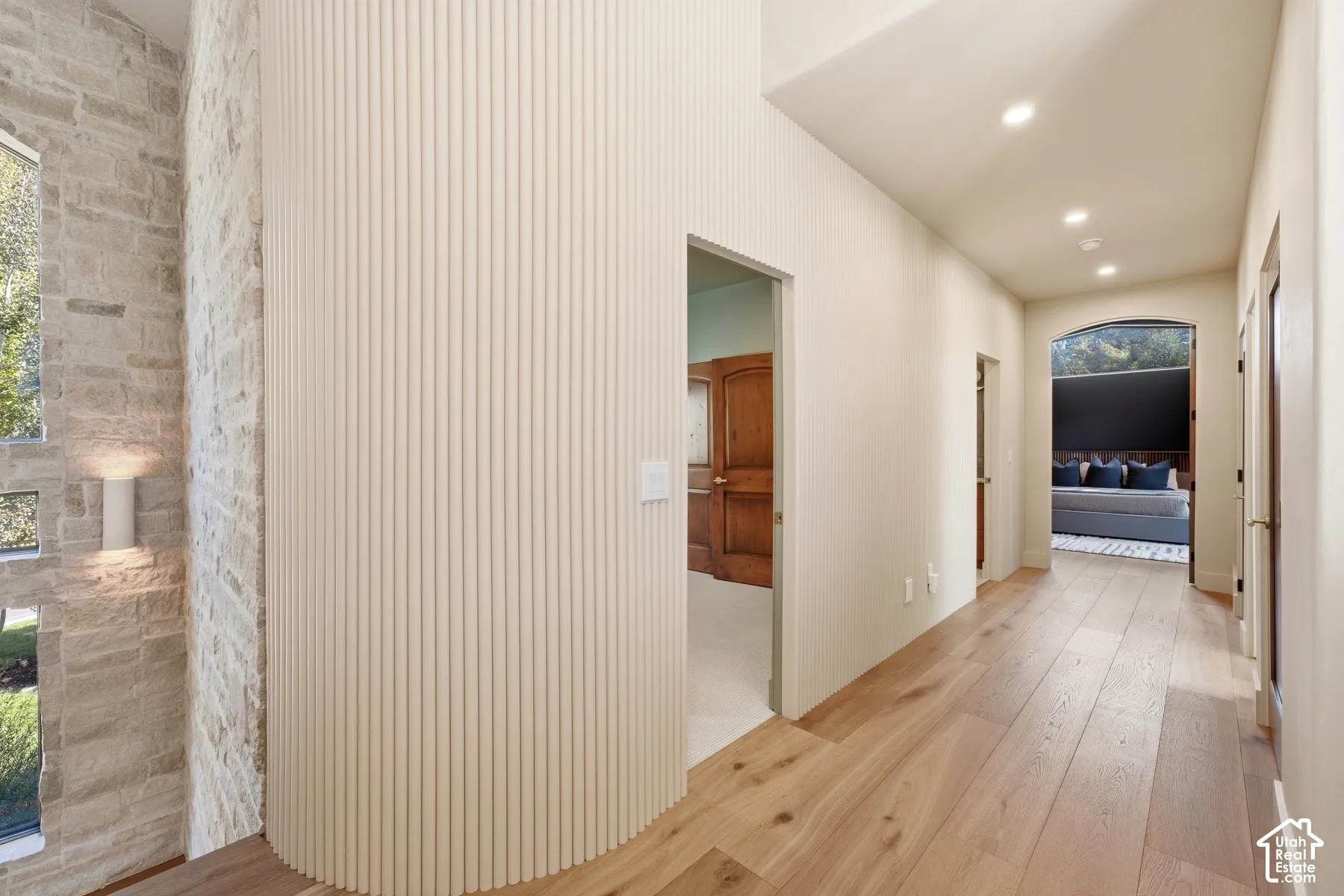 Wood-finish flooring throughout, featuring a stone accent wall, recessed lighting, and a paneled accent wall