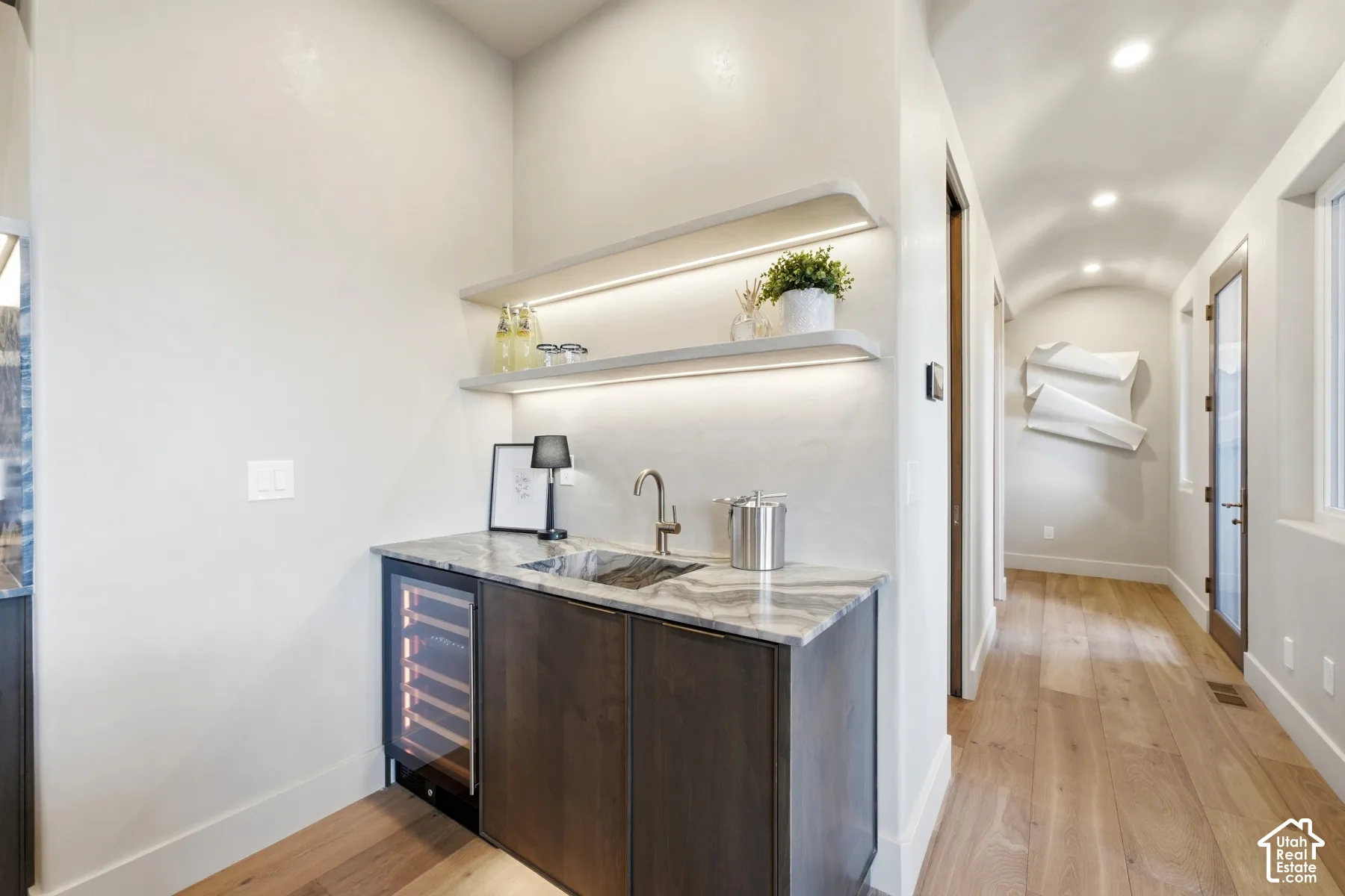 Built-in wet bar with a wine refrigerator, undermount sink, and stone-finish countertop