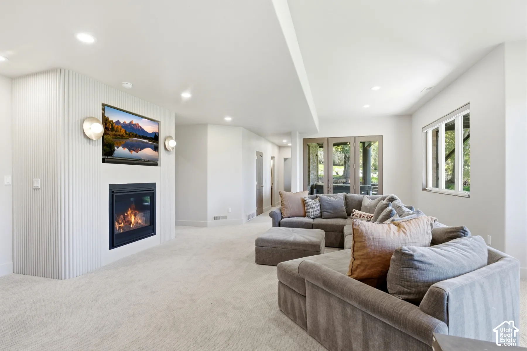 Recessed lighting, light-colored carpeting, built-in fireplace, and double glass doors