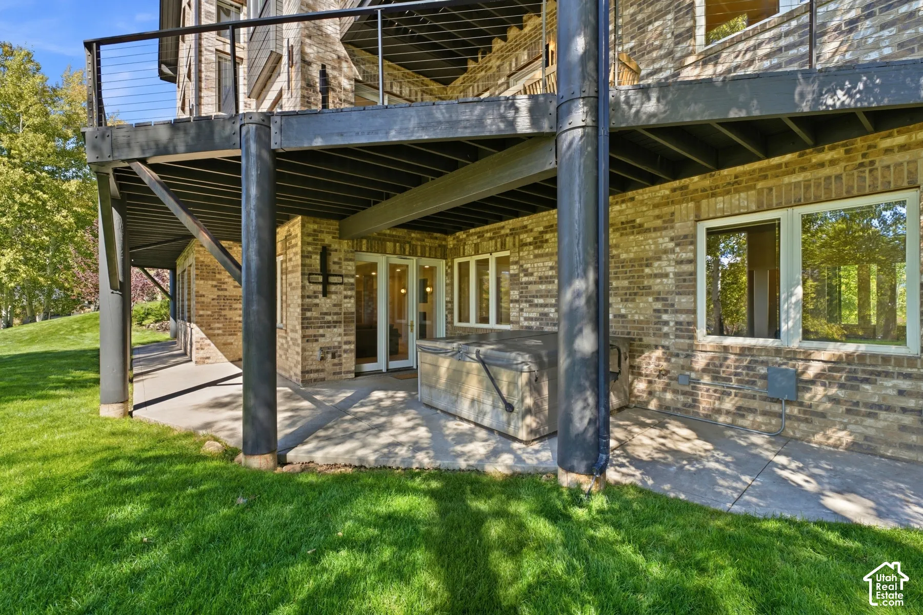 Ground-level patio with a covered section, brick exterior, and a built-in outdoor spa