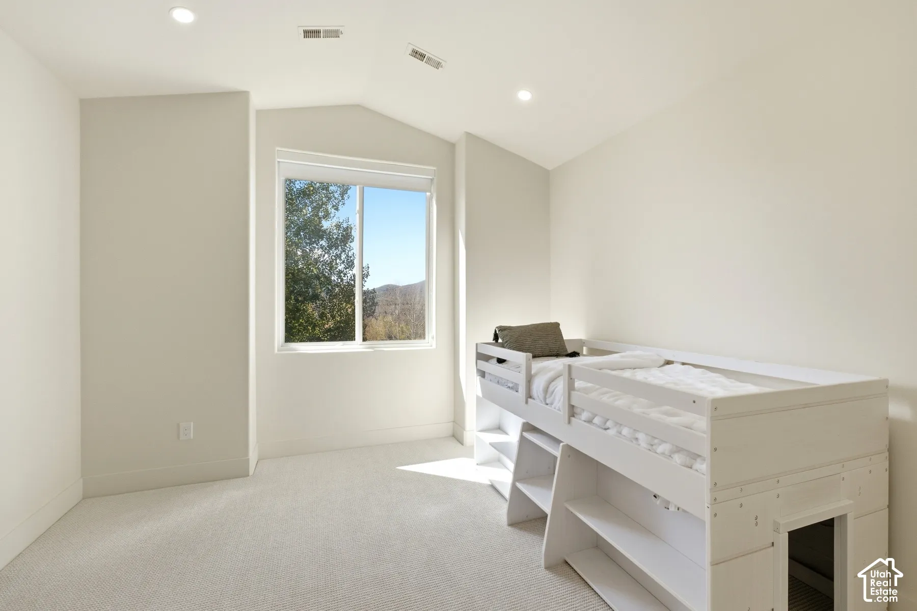 Recessed lighting, sloped ceiling, bright window, neutral wall paint, and light-colored carpeting