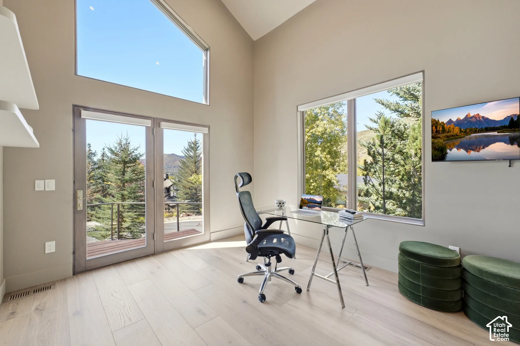 Vaulted ceiling, expansive windows, wood-finish flooring, glass panel double doors, and large picture window
