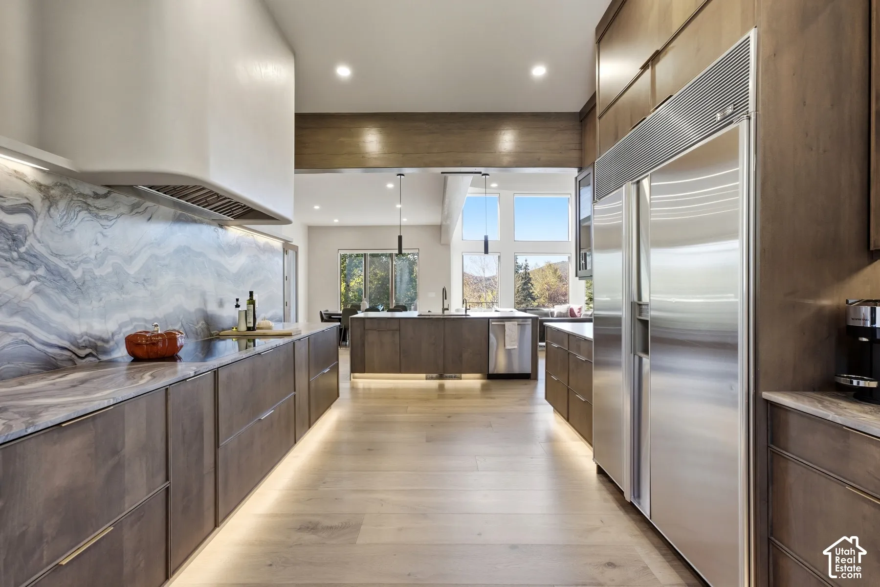 Gourmet kitchen featuring a built-in stainless steel refrigerator, extensive wood cabinetry, and a large natural stone backsplash