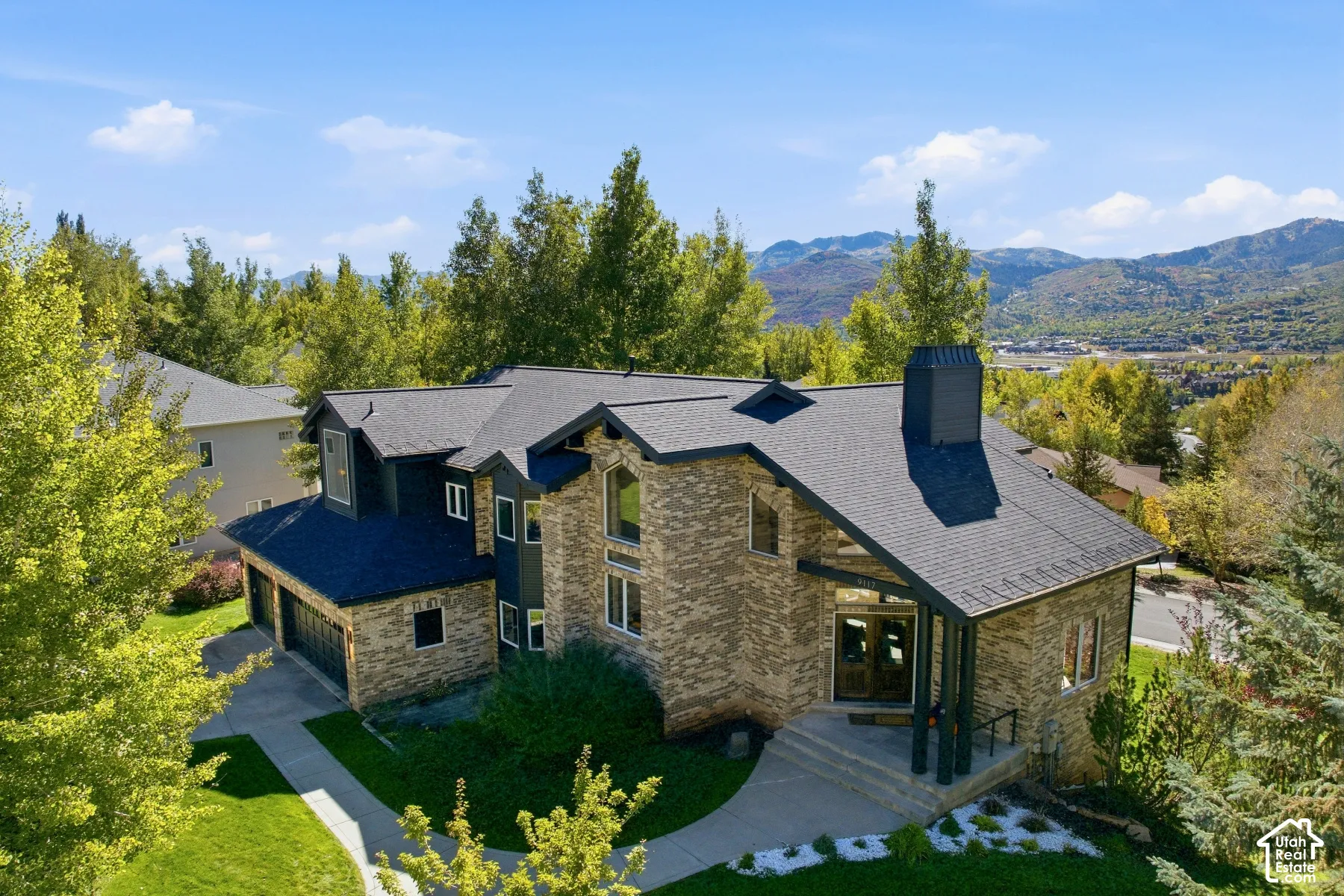 Multi-level residence featuring a stone and siding exterior, a multi-car garage, and a covered entry