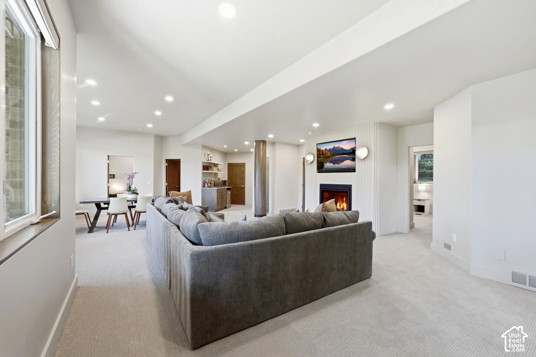 Spacious open-concept living area featuring recessed lighting, a built-in fireplace, and a dedicated wet bar with shelving