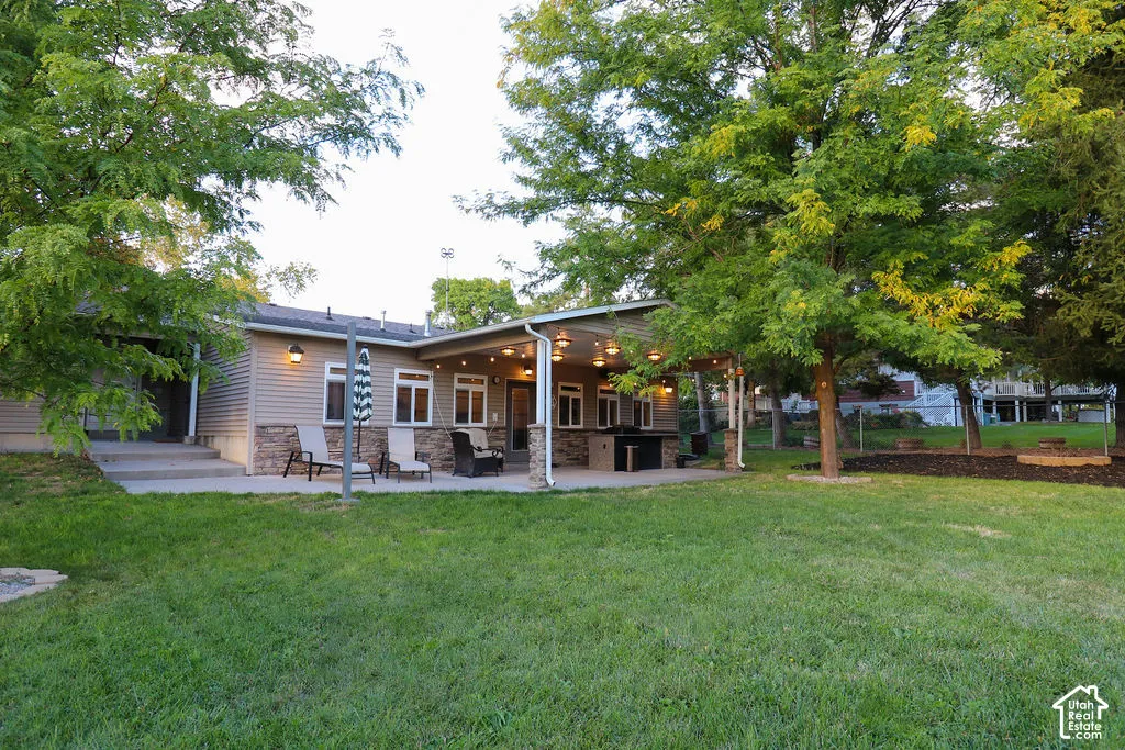 Expansive outdoor patio with a covered section, stone accents, and built-in grill area