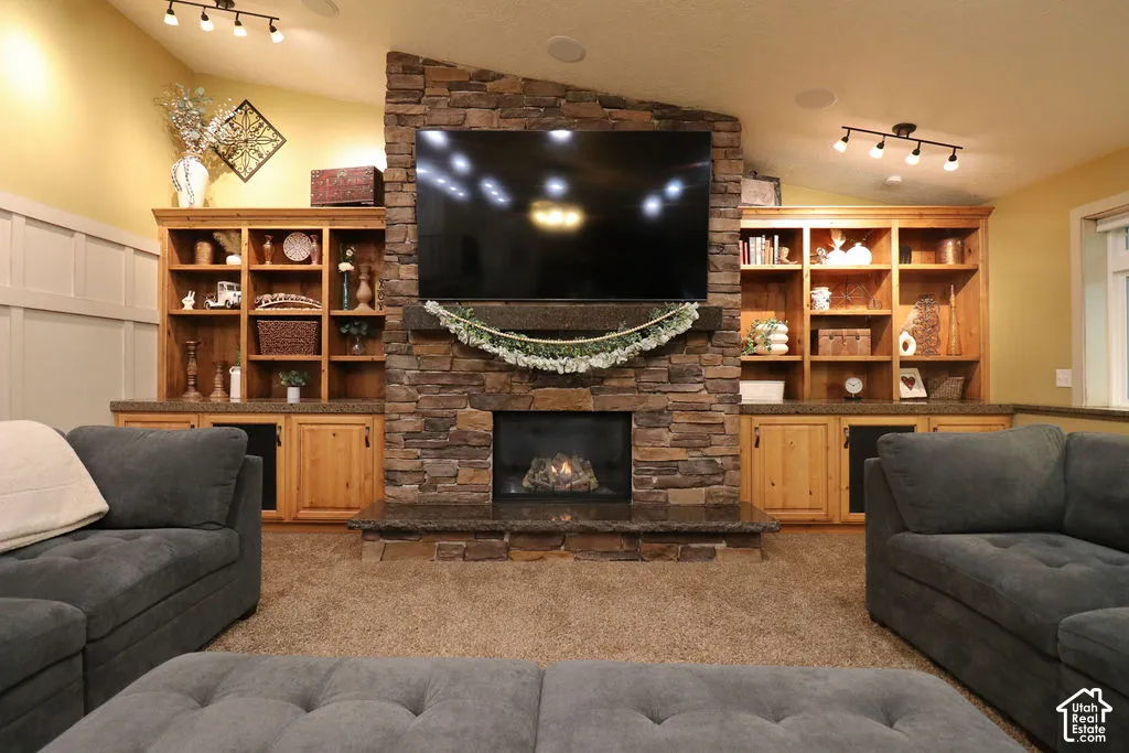 Stone-clad fireplace with hearth, integrated wooden built-in shelving, panel wainscoting, and recessed lighting