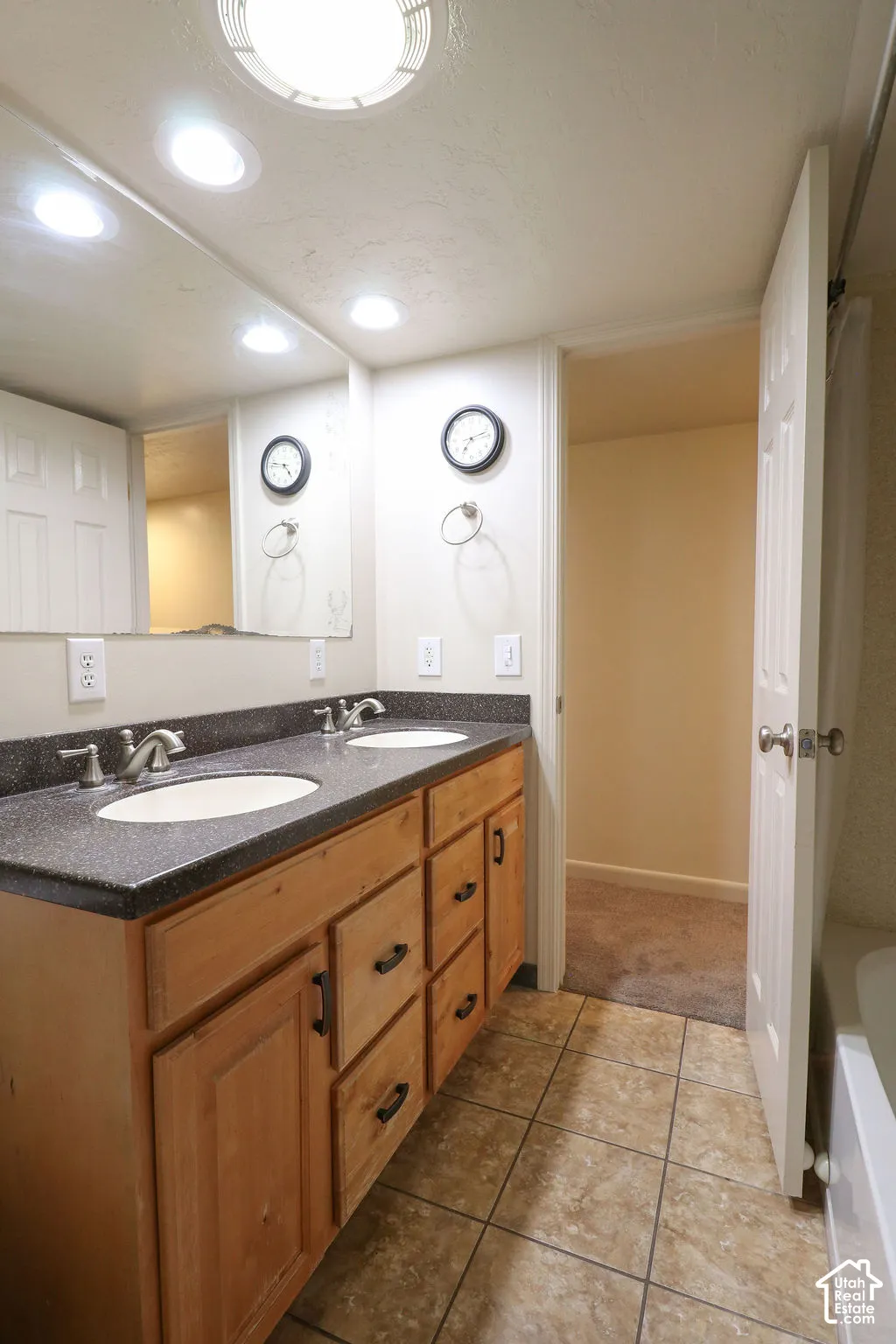 Double vanity with wood-finish cabinetry, dual undermount sinks, and a dark countertop