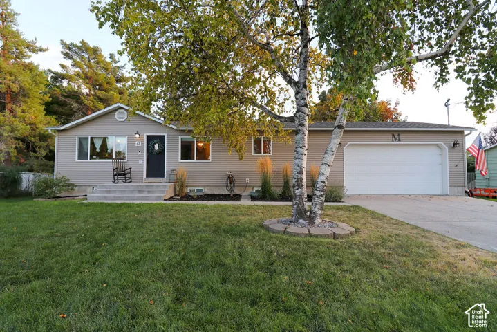 Single-story residence featuring light gray siding, a prominent two-car garage with white door, and a concrete driveway
