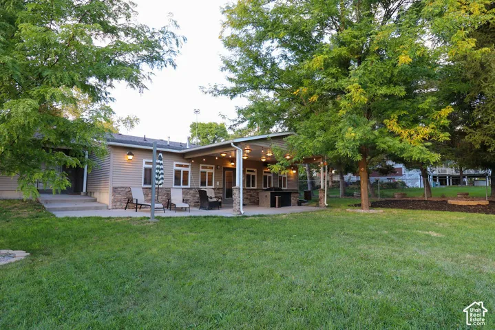 Expansive outdoor patio with a covered section, stone accents, and built-in grill area