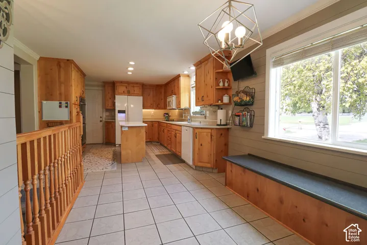 Kitchen featuring wood cabinetry, white tile flooring, white appliances, a center island with countertop, and a built-in window bench