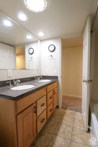 Double vanity with wood-finish cabinetry, dual undermount sinks, and a dark countertop