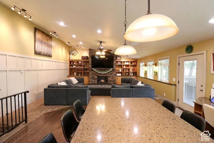 Integrated living space featuring a stone-clad fireplace with hearth, built-in shelving, and recessed lighting