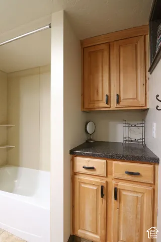 Built-in cabinetry with dark hardware, dark countertop, and integrated shelving