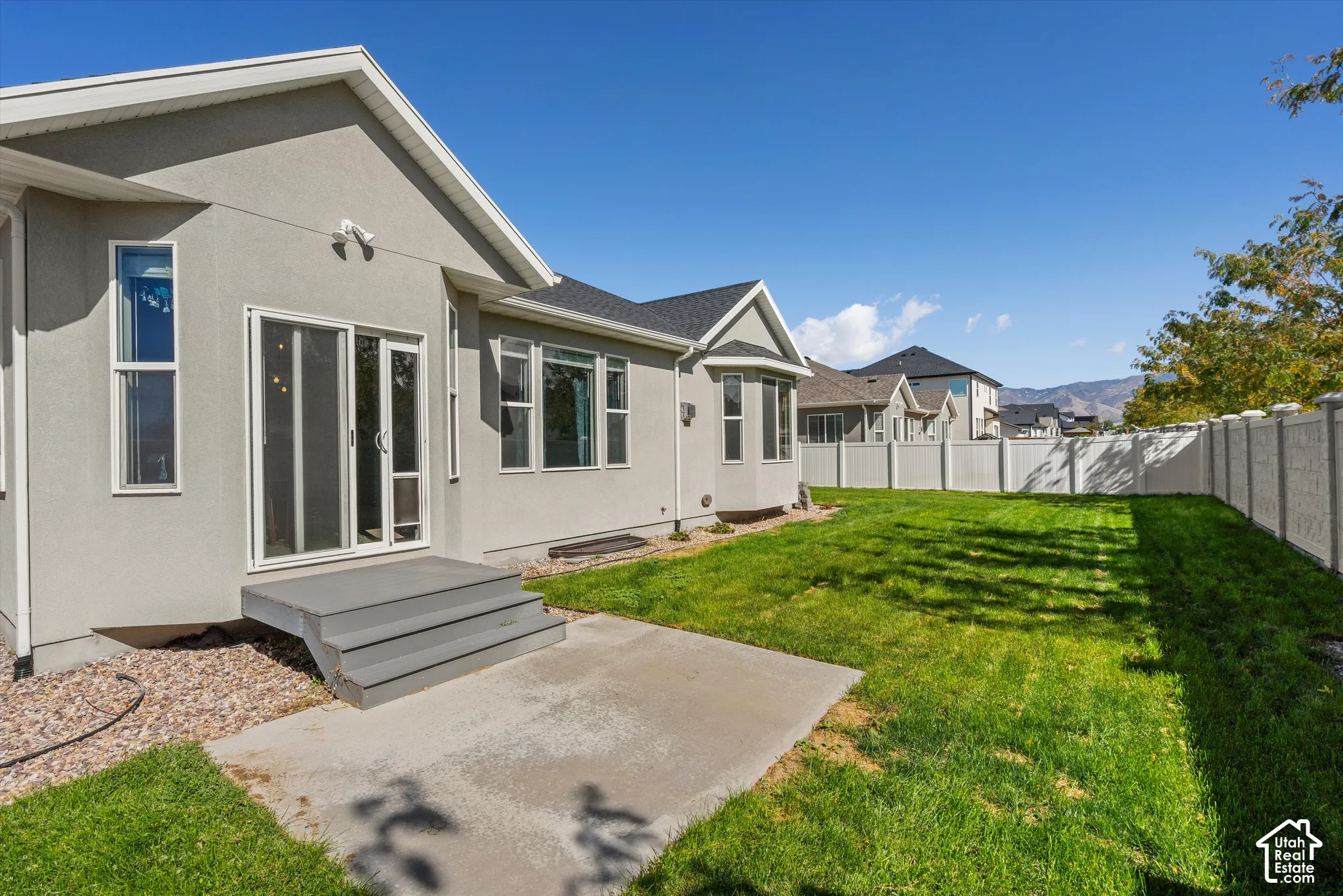 Expansive backyard featuring a manicured lawn, concrete patio, and privacy fencing