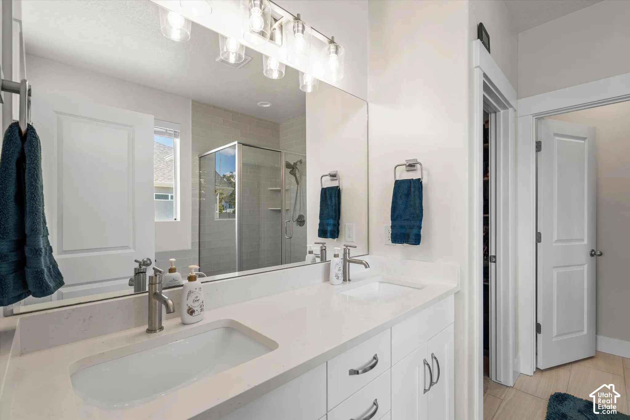 Double vanity featuring white cabinetry and light-toned countertops