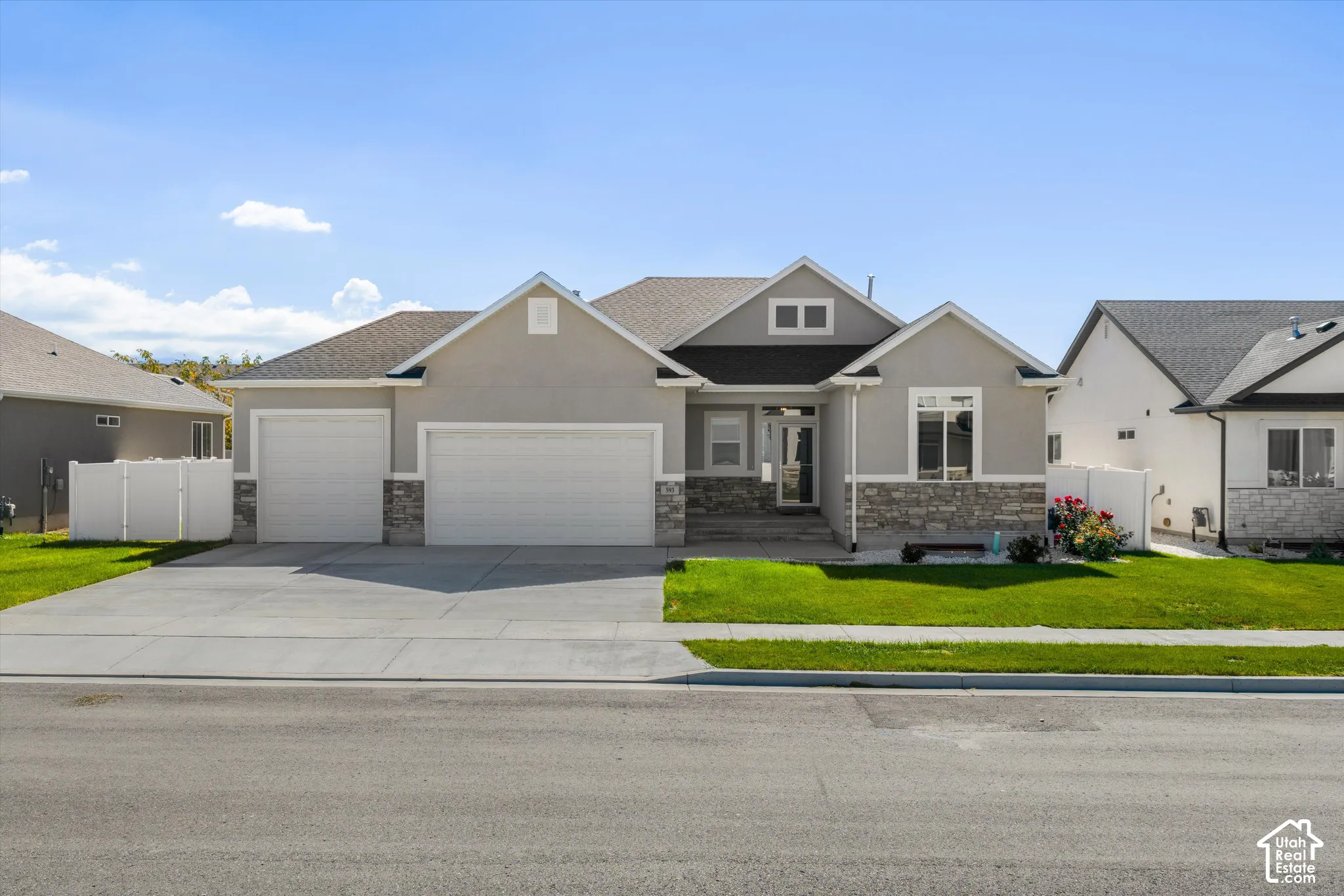 Stucco and stone exterior with a three car garage and a concrete driveway