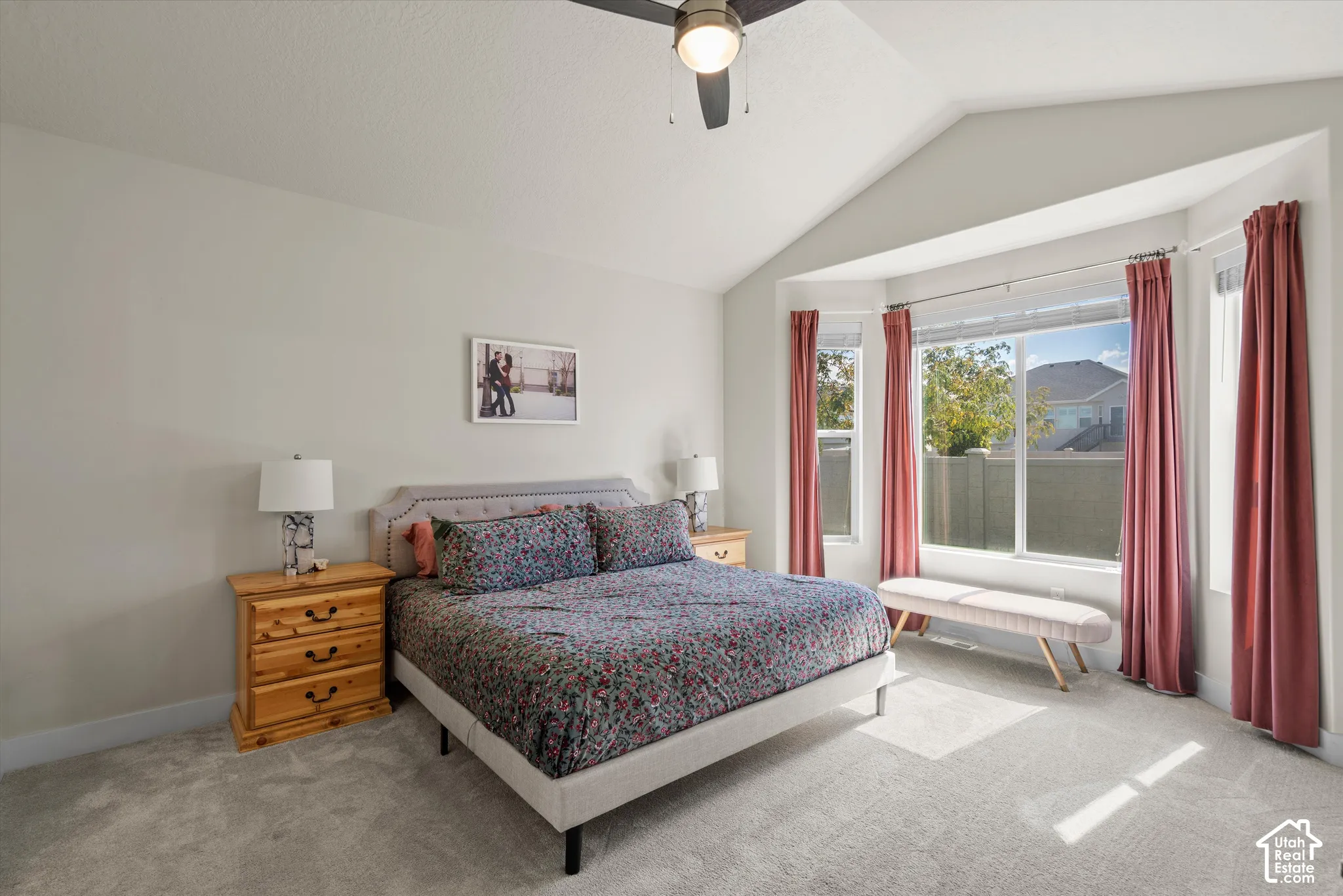 Vaulted ceiling with a ceiling fan, bay window with multiple panes, light gray wall paint, and light gray carpet flooring