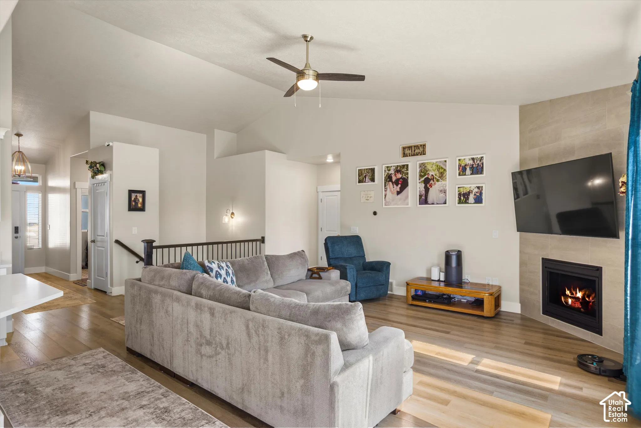 Vaulted ceilings with a ceiling fan, recessed fireplace with tile surround, wood-finish flooring, and built-in wall sconces