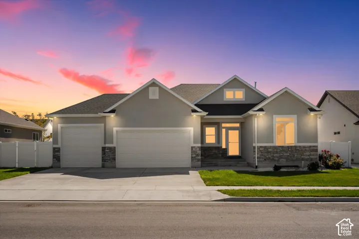 Contemporary exterior featuring a three-car garage, stone and stucco facade, and a covered entry