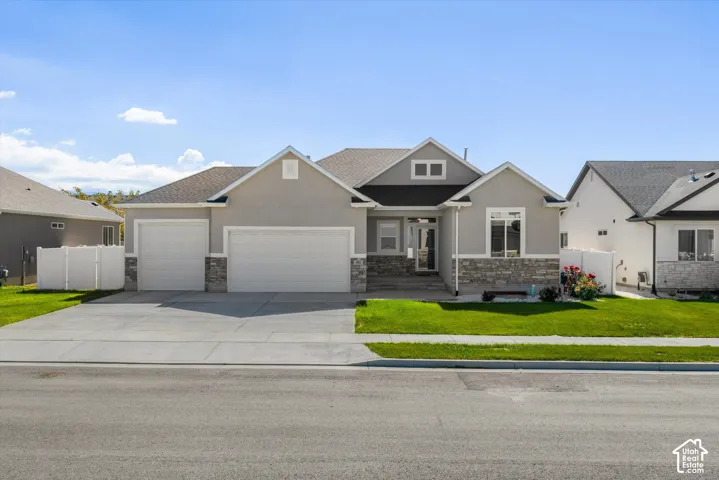Stucco and stone exterior with a three car garage and a concrete driveway