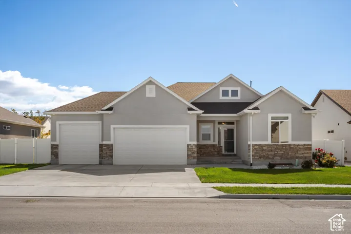 Gray stucco exterior with a stone accent facade, featuring a three-car garage and a paved driveway
