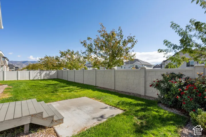 Expansive backyard featuring a concrete patio, composite deck steps, and a privacy fence