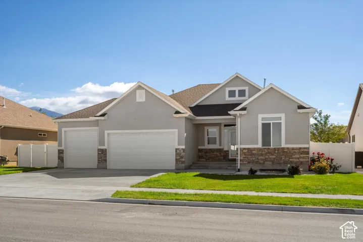 Stucco exterior with stone accents, three-car garage, and a concrete driveway